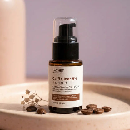 SACHET Caffi Clear 5% Serum bottle on a neutral background with coffee beans and dried flowers.